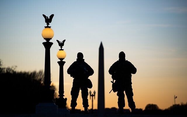 US National Guard soldiers are seen in silhouette as they keep guard in front of the Capitol Building and near the Washington Monument in Washington, DC on January 19, 2021, ahead of the 59th inaugural ceremony for President-elect Joe Biden and Vice President-elect Kamala Harris. (Photo by ROBERTO SCHMIDT / AFP)