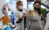 A health worker administers a dose of the Pfizer-BioNtech COVID-19 vaccine to a pregnant woman at a Clalit Health Services clinic in Tel Aviv on January 23, 2021. (AFP)