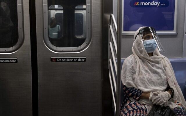 In this file photo taken on July 16, 2020, a woman wearing a face mask and shield sits in a subway train during rush hour amid the coronavirus pandemic in New York City (Johannes EISELE / AFP) In this file photo taken on July 16, 2020, a woman wearing a face mask and shield sits in a subway train during rush hour amid the coronavirus pandemic in New York City (Johannes EISELE / AFP)