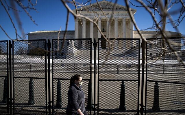 A woman walks past protective fencing erected around the US Supreme Court, on January 10, 2021 in Washington, DC. (Al Drago/Getty Images/AFP A woman walks past protective fencing erected around the US Supreme Court, on January 10, 2021 in Washington, DC. (Al Drago/Getty Images/AFP
