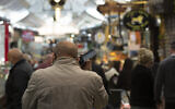 A man speaks on his mobile phone at the Mahane Yehuda market in Jerusalem, December 23, 2020. (Maya Alleruzzo/AP)