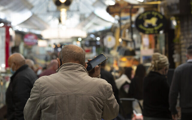A man speaks on his mobile phone at the Mahane Yehuda market in Jerusalem, December 23, 2020. (Maya Alleruzzo/AP) A man speaks on his mobile phone at the Mahane Yehuda market in Jerusalem, December 23, 2020. (Maya Alleruzzo/AP)