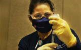 Houston Health Department LVN Alicia Meza prepares a dose of COVID-19 vaccine Sunday, Jan. 3, 2021, at a Houston Health Department's COVID-19 vaccine clinic in Houston. The department vaccinated 1,008 people who qualify under Phase 1A or Phase 1B of the state's guidelines at the clinic's first day on Saturday. (Yi-Chin Lee/Houston Chronicle via AP)
