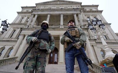In this Jan. 6, 2021 file photo, armed men stand on the steps at the State Capitol after a rally in support of President Donald Trump in Lansing, Michigan (AP Photo/Paul Sancya, File)