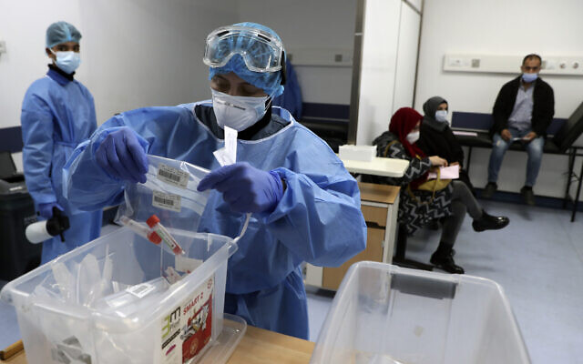 A nurse in protective clothing holds coronavirus testing material, at a center in the Rafik Hariri University Hospital in Beirut, Lebanon, January 11, 2021. (AP Photo/Bilal Hussein)