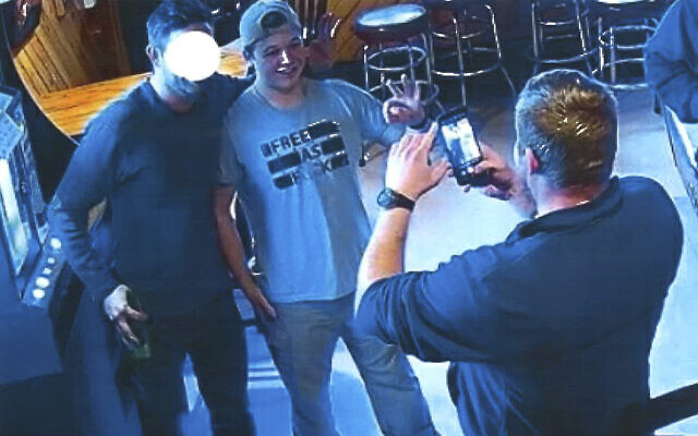 In this image from video provided by the Kenosha County District Attorney, Kyle Rittenhouse poses for a photo at Pudgy's Pub in Mount Pleasant, Wis., on Jan. 5, 2021, the day he was arraigned on charges related to the killing of two people at an August protest in Kenosha. Prosecutors presented this photo and others as evidence of Rittenhouse consorting with white supremacists, citing the use of the “OK” sign, which has been co-opted as a sign of “white power.” Rittenhouse's attorney said he is not and has never been a member of a white supremacist group. Rittenhouse's shirt and the face of the man posing with him were redacted by the source. (Courtesy of Kenosha County District Attorney via AP) In this image from video provided by the Kenosha County District Attorney, Kyle Rittenhouse poses for a photo at Pudgy's Pub in Mount Pleasant, Wis., on Jan. 5, 2021, the day he was arraigned on charges related to the killing of two people at an August protest in Kenosha. Prosecutors presented this photo and others as evidence of Rittenhouse consorting with white supremacists, citing the use of the “OK” sign, which has been co-opted as a sign of “white power.” Rittenhouse's attorney said he is not and has never been a member of a white supremacist group. Rittenhouse's shirt and the face of the man posing with him were redacted by the source. (Courtesy of Kenosha County District Attorney via AP)