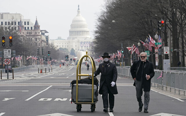Danish Rozario, left, of Silver Spring, Maryland, wheels the baggage down Pennsylvania Avenue for a guest at the Trump Hotel in Washington, January 15, 2021, ahead of the inauguration of President-elect Joe Biden and Vice President-elect Kamala Harris. (AP Photo/Susan Walsh) Danish Rozario, left, of Silver Spring, Maryland, wheels the baggage down Pennsylvania Avenue for a guest at the Trump Hotel in Washington, January 15, 2021, ahead of the inauguration of President-elect Joe Biden and Vice President-elect Kamala Harris. (AP Photo/Susan Walsh)