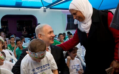 Illustrative: Prime Minister Benjamin Netanyahu poses for a photograph with pupils on the first day of school in the Israeli Arab town of Tamra, Thursday, September 1, 2016. (AP/Sebastian Scheiner)