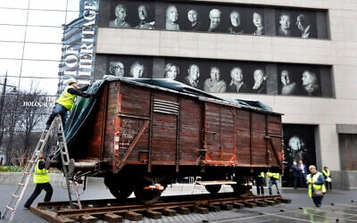 Illustrative: Portraits of Holocaust survivors are displayed at the Museum of Jewish Heritage as a vintage German train car, like those used to transport people to Auschwitz and other death camps, is uncovered on tracks outside the museum, in New York, Sunday, March 31, 2019.  (AP Photo/Richard Drew)