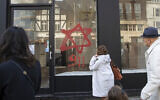 People look at anti-Semitic graffiti on a shop window in Belsize Park, North London, December 29, 2019 (Aaron Chown/PA via AP)