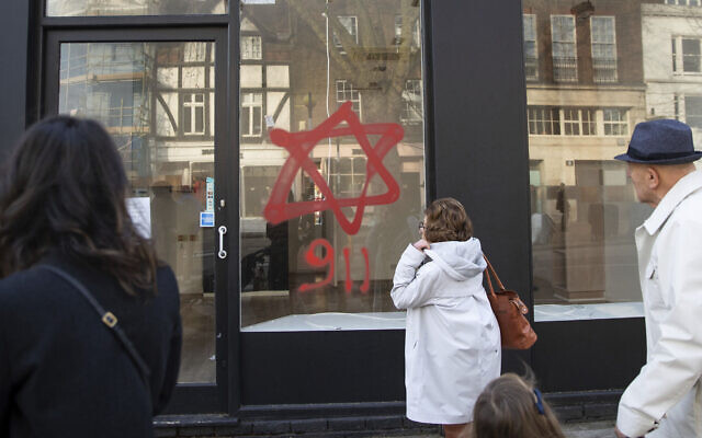 People look at anti-Semitic graffiti on a shop window in Belsize Park, North London, December 29, 2019 (Aaron Chown/PA via AP) People look at anti-Semitic graffiti on a shop window in Belsize Park, North London, December 29, 2019 (Aaron Chown/PA via AP)