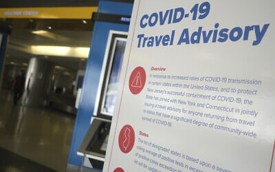 Illustrative: A sign warns airline passengers about a COVID-19 travel advisory at Newark Liberty International Airport in Newark, New Jersey, July 1, 2020. (Seth Wenig/AP)