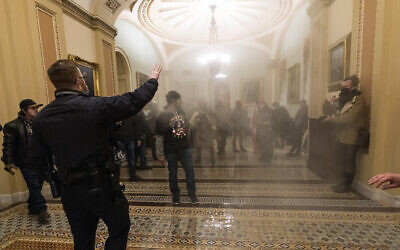 Smoke fills the walkway outside the Senate Chamber as supporters of US President Donald Trump are confronted by US Capitol Police officers inside the Capitol, January 6, 2021 in Washington.  (AP Photo/Manuel Balce Ceneta)