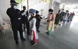 Health workers check the body temperature of volunteers participating in a trial run of a COVID-19 vaccine delivery system in Ahmedabad, India, January 8, 2021. (AP Photo/Ajit Solanki)