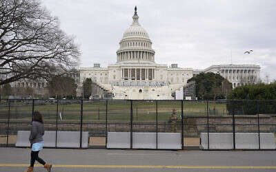 A woman walks past security fencing protecting the West Front of the US Capitol in Washington, January 8, 2021, as preparations take place for President-elect Joe Biden's inauguration after Trump supporters stormed the building. (AP Photo/Patrick Semansky)