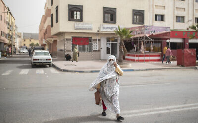 A woman draped in traditional Sahraoui wear known as 'Malhafa' crosses a road in Dakhla city, Western Sahara, Monday, Dec. 21, 2020. (AP Photo/Mosa'ab Elshamy)