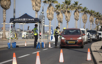 Police officers check cars at a checkpoint during a nationwide lockdown to curb the spread of the coronavirus, in Tel Aviv, January 10, 2021. (AP/Sebastian Scheiner)