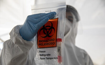 An Israeli health care professional holds a COVID-19 test sample in a bag at a testing center in Jerusalem during a nationwide lockdown to curb the spread of the coronavirus, Jan. 10, 2021. (AP Photo/Ariel Schalit)