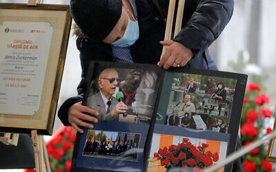 A man adjusts images of Iancu Tucarman, during his funeral, at a Jewish cemetery in Bucharest, Romania, January 11, 2021. (AP/ Vadim Ghirda)