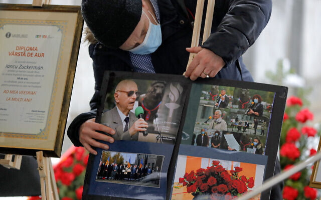 A man adjusts images of Iancu Tucarman, during his funeral, at a Jewish cemetery in Bucharest, Romania, January 11, 2021. (AP/ Vadim Ghirda) A man adjusts images of Iancu Tucarman, during his funeral, at a Jewish cemetery in Bucharest, Romania, January 11, 2021. (AP/ Vadim Ghirda)