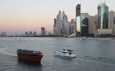 Tourists on a yacht as they pass a traditional dhow serving a dinner cruise, in Dubai, United Arab Emirates, January 12, 2021 (AP Photo/Kamran Jebreili)