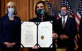 House Speaker Nancy Pelosi of Calif., displays the signed article of impeachment against US President Donald Trump in an engrossment ceremony before transmission to the Senate for trial on Capitol Hill, in Washington, Wednesday, January 13, 2021. (AP Photo/Alex Brandon)