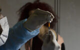 A medical professional prepares to administer the Pfizer COVID-19 vaccine to a woman at a makeshift vaccination center in a sports arena in Jerusalem, Jan. 14, 2021. (AP Photo/Maya Alleruzzo)