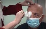 Prof. Irit Bahar, director of the Ophthalmology Department at Rabin Medical Center, removes the bandages from Jamal Furani, after he got the artificial cornea implant developed by CorNeat Vision (Channel 13 screenshot)