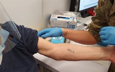 A photo of Auschwitz survivor Herschel Herskovic receiving his COVID shot in the same arm that bears his camp number tattoo taken by his son (Twitter)