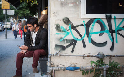 Illustrative: A man listens to earbuds in Tel Aviv on November 14, 2015. (Esther Rubyan/FLASH90)