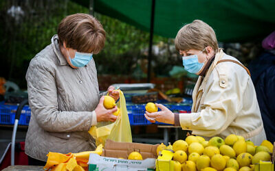 Israeli women inspect lemons at the market in the northern city of Safed on December 9, 2020. (David Cohen/ Flash90)