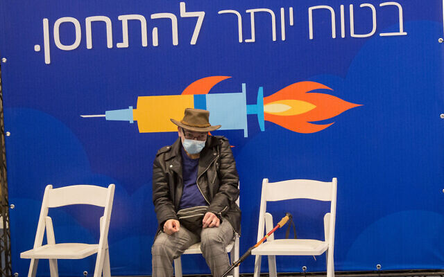 A man waits at a vaccination center in Tel Aviv on December 31, 2020. (Miriam Alster/Flash90) A man waits at a vaccination center in Tel Aviv on December 31, 2020. (Miriam Alster/Flash90)