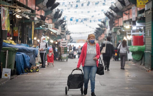 A woman walks through Tel Aviv's Hatikva Market during a nationwide lockdown, on January 3, 2021 (Miriam Alster/Flash90) A woman walks through Tel Aviv's Hatikva Market during a nationwide lockdown, on January 3, 2021 (Miriam Alster/Flash90)