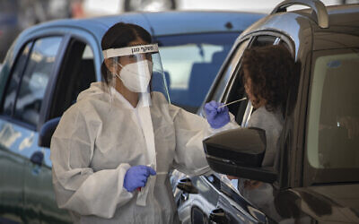 Health care workers take coronavirus test samples of Israelis in a drive through complex in Jerusalem, January 4, 2021. (Olivier Fitoussi/Flash90)