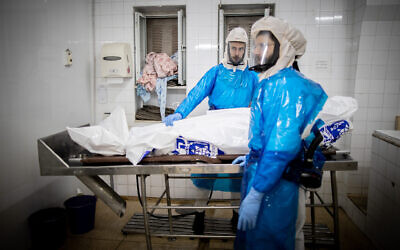 Workers from Chevra Kadisha Kehilat Yerushalayim prepare a body before a funeral at a morgue for people who died from COVID-19, at the Sanhedriya Cemetery in Jeursalem, January 25, 2021. (Yonatan Sindel/Flash90)