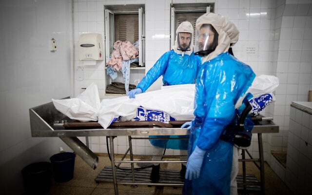 Workers from Chevra Kadisha Kehilat Yerushalayim prepare a body before a funeral at a morgue for people who died from COVID-19, at the Sanhedriya Cemetery in Jeursalem, January 25, 2021. (Yonatan Sindel/Flash90) Workers from Chevra Kadisha Kehilat Yerushalayim prepare a body before a funeral at a morgue for people who died from COVID-19, at the Sanhedriya Cemetery in Jeursalem, January 25, 2021. (Yonatan Sindel/Flash90)