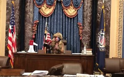 Jacob Chansley sits in Vice President Mike Pence's seat in the Senate on January 6, 2021 before leaving him a threatening note. (Screencapture/ YouTube)