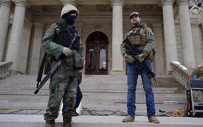 Armed civilians stand on the steps of the Michigan state capitol building after a rally in support of US President Donald Trump in Lansing, Michigan, January 6, 2021. (AP Photo/Paul Sancya)