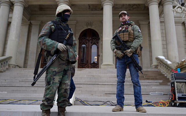 Armed civilians stand on the steps of the Michigan state capitol building after a rally in support of US President Donald Trump in Lansing, Michigan, January 6, 2021. (AP Photo/Paul Sancya) Armed civilians stand on the steps of the Michigan state capitol building after a rally in support of US President Donald Trump in Lansing, Michigan, January 6, 2021. (AP Photo/Paul Sancya)