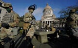 Members of the Washington National Guard stand near the Legislative Building at the state Capitol in Olympia, Washington, January 10, 2021. (AP Photo/Ted S. Warren)