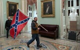 A supporter of US President Donald Trump carries a Confederate flag in the US Capitol Rotunda in Washington, DC, January 6, 2021. (Saul Loeb/AFP)