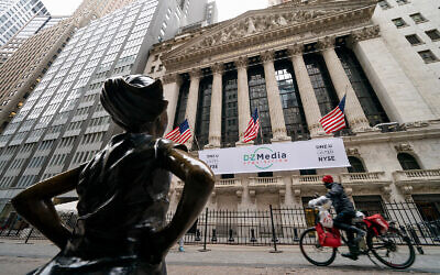 A delivery man riding a bicycle passes the New York Stock Exchange and Fearless Girl, a bronze sculpture by Kristen Visbal, in New York, January 27, 2021. (AP Photo/John Minchillo) A delivery man riding a bicycle passes the New York Stock Exchange and Fearless Girl, a bronze sculpture by Kristen Visbal, in New York, January 27, 2021. (AP Photo/John Minchillo)