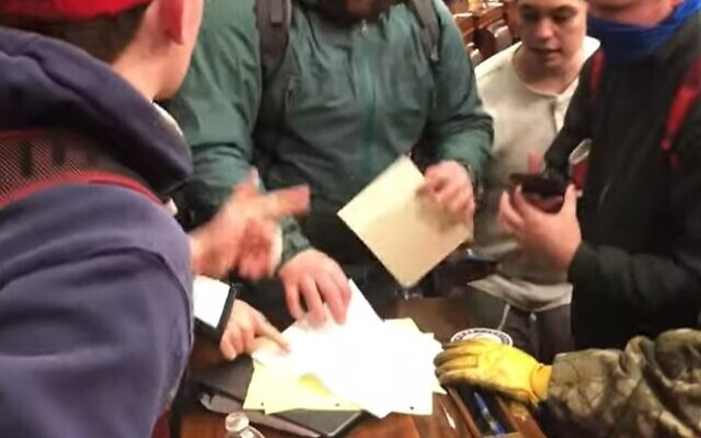 Rioters search through documents found in the Senate on January 6, 2021 (Screenshot/YouTube)