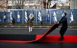 A Kosovo worker drags the red carpet next to Kosovo's and Israel's flags displayed during a ceremony at the headquarters of the Foreign Ministry in Pristina on February 1, 2021 (Armend NIMANI / AFP)
