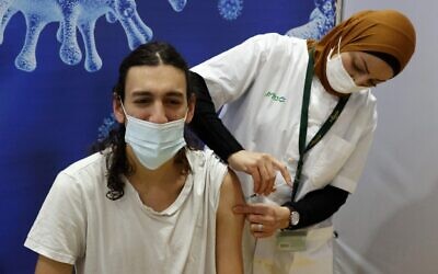 Illustrative: An Israeli health worker administers a dose of the Pfizer-BioNtech Covid-19 vaccine at Clalit Health Services, in a gymnasium in the central Israeli city of Hod Hasharon, on February 4, 2021. (JACK GUEZ / AFP)