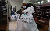 An employee of Palestine Post carries a courier bag at a post office in the West Bank town of Nablus, on February 7, 2021. (JAAFAR ASHTIYEH / AFP)