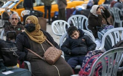 A mask-clad Palestinian woman and a boy wait with luggage at the Rafah border crossing's departure area to travel from the Gaza Strip into Egypt, on February 9, 2021. (Said Khatib/AFP)