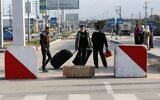 Palestinians walk with luggage at the Rafah border crossing's departure area to travel from the Gaza Strip into Egypt, on February 9, 2021 (SAID KHATIB / AFP)