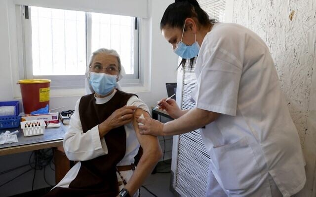 A French nun living in Israel receives a dose of COVID-19 coronavirus vaccine at the Tel Aviv Sourasky Medical Centre for foreign nationals in Tel Aviv on February 9, 2021 during a campaign to vaccinate foreign workers and refugees against coronavirus. (JACK GUEZ / AFP)