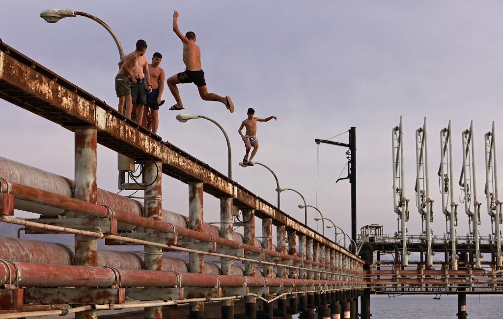 Youths jump into the Red Sea water off an abandoned oil jetty in Israel's southern port city of Eilat on February 9, 2021. (MENAHEM KAHANA / AFP) Youths jump into the Red Sea water off an abandoned oil jetty in Israel's southern port city of Eilat on February 9, 2021. (MENAHEM KAHANA / AFP)